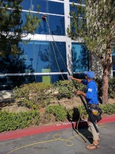 washing windows with purified water on telescopic pole near Corona